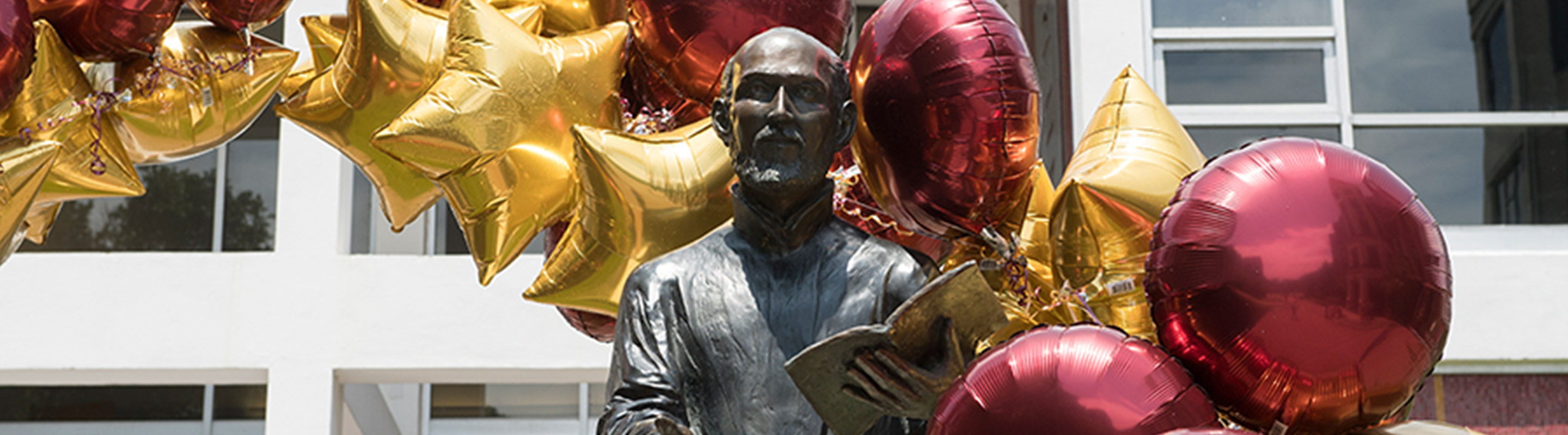 STraight on shot of Ignatius statue with maroon and gold balloons