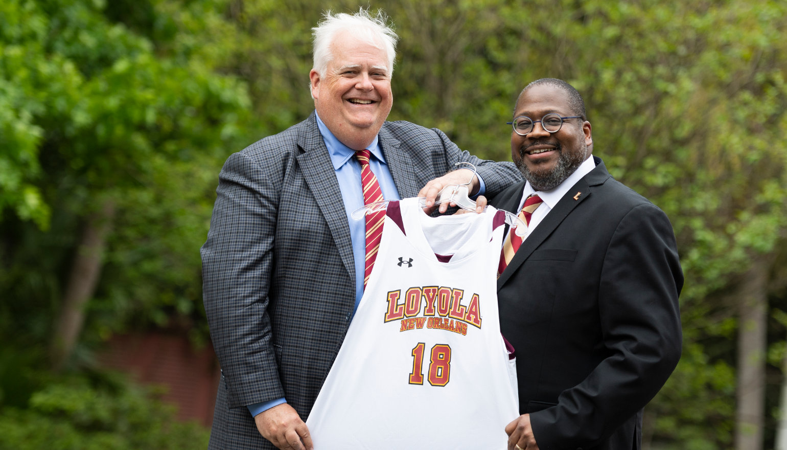 Stephen Landry '83, chair of the Board of Trustees, presents Dr. Xavier Cole with a #18 basketball jersey